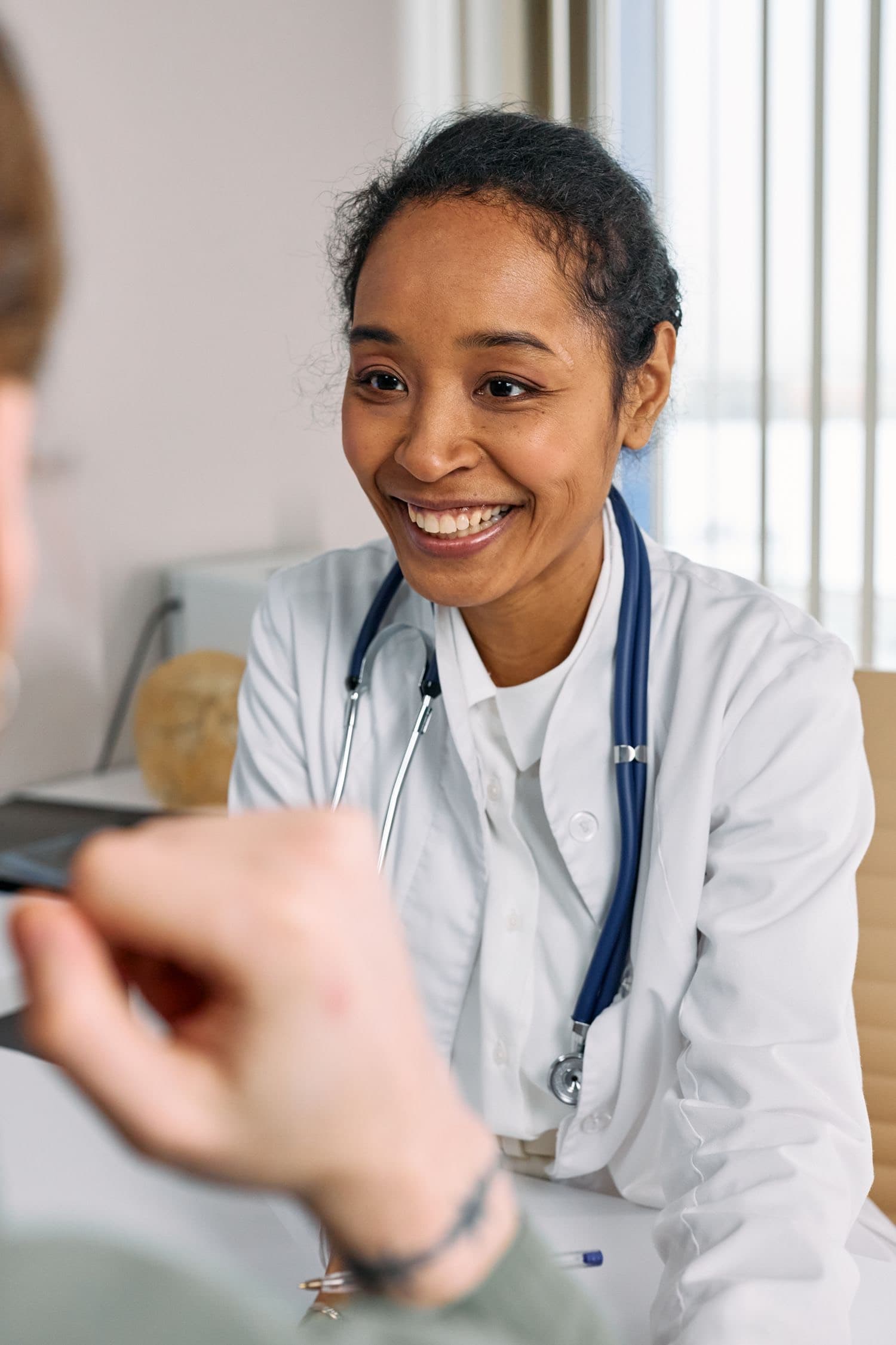 Profissional de saúde sorrindo durante uma consulta acolhedora com paciente